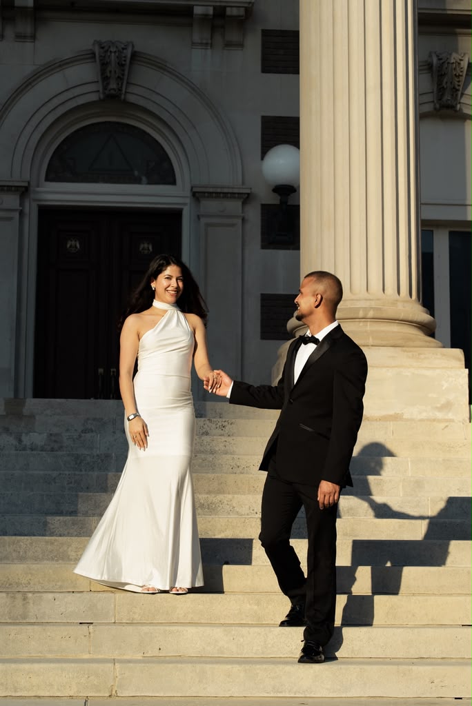 A couple holding hands in front of a beautiful stone building